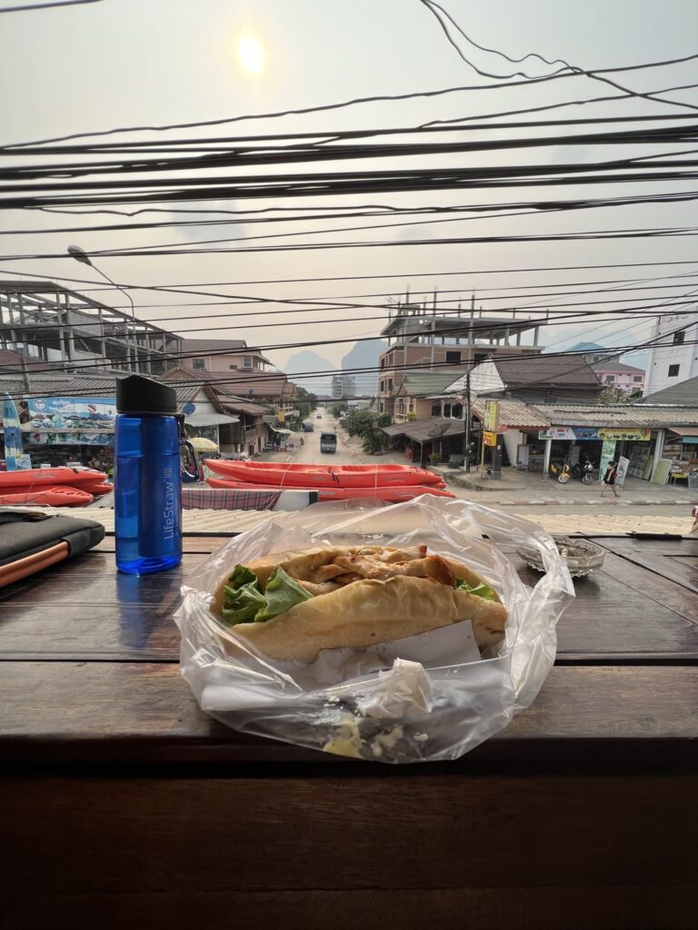 Sandwich and water bottle with street view, Vang Vieng, Vientiane Province, Laos.
