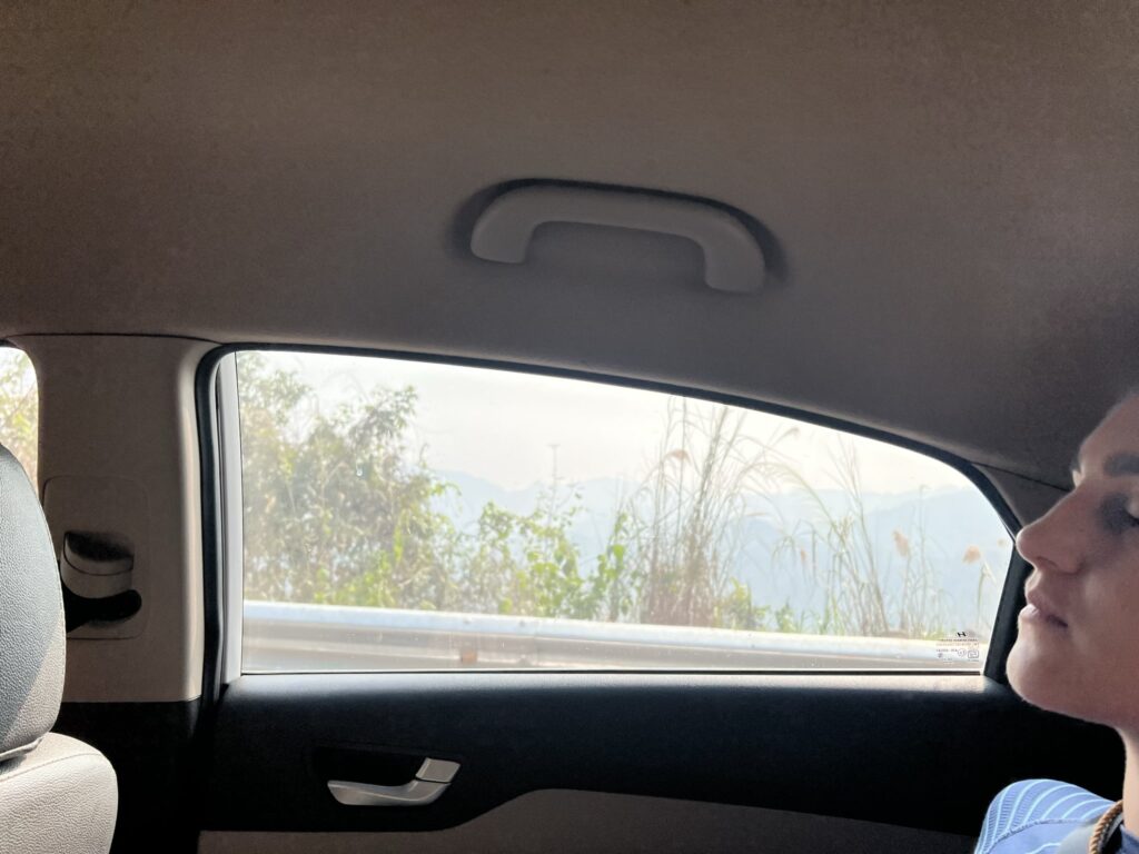 Person looking out car window at mountains, Mai Chau, Phú Thọ Province, Vietnam.