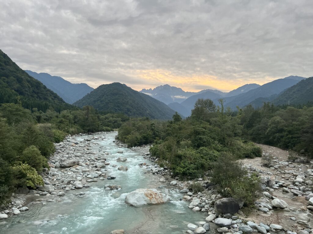 Winding rocky river through green mountains at sunset, Kamiichi, Toyama Prefecture, Japan.