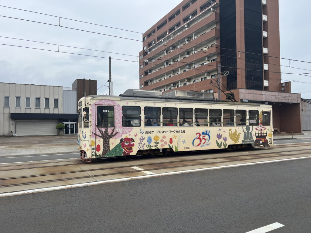 Cream colored tram with colorful decorations, Takaoka, Toyama Prefecture, Japan.