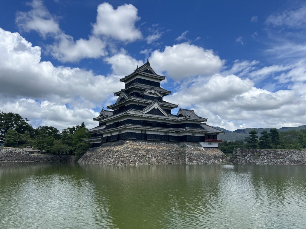 Black multi-tiered Japanese castle in a moat, Matsumoto, Nagano Prefecture, Japan.